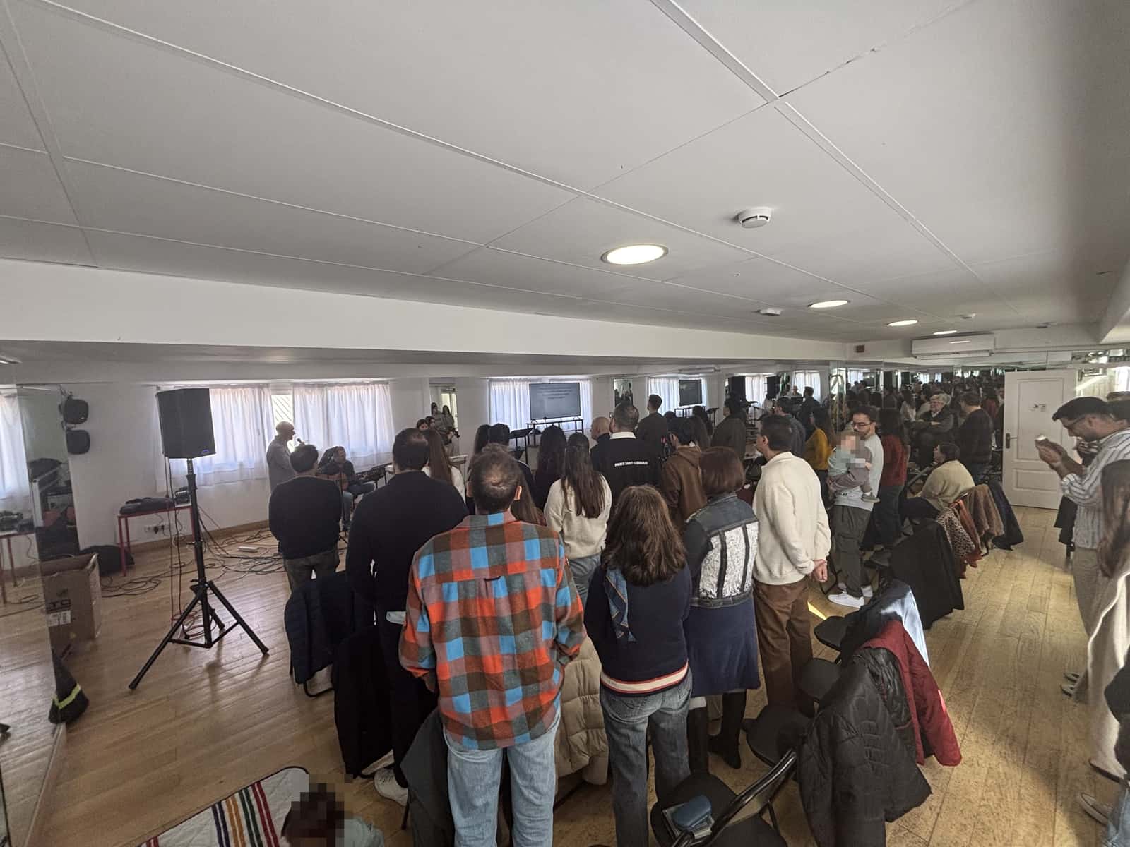 Personas de pie cantando durante el culto del domingo