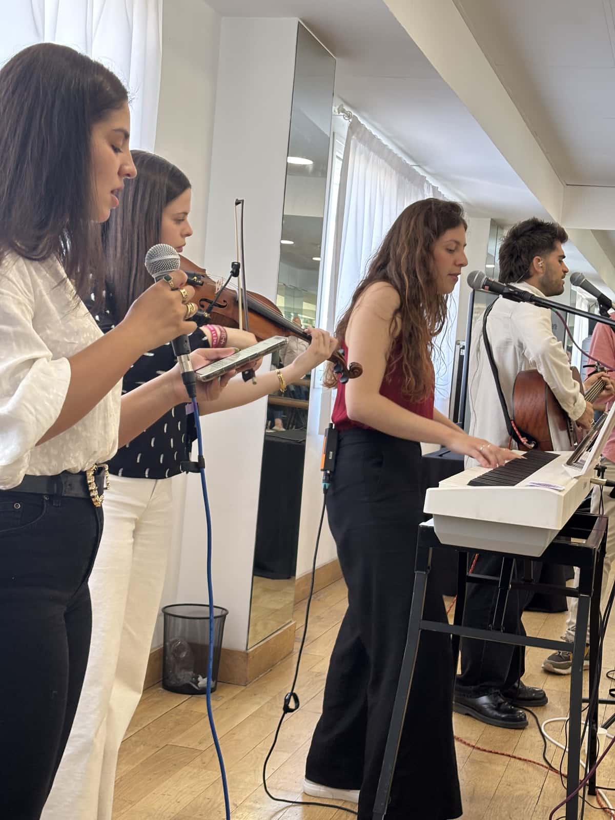 Grupo de música tocando violín, teclado y guitarra en el culto