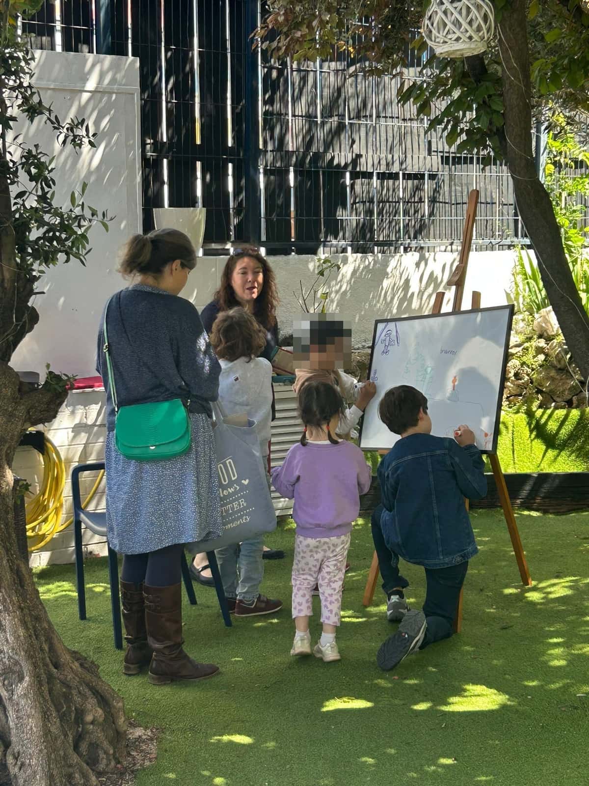 Niños hacen una actividad con una pizarra en el jardín